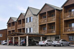 A multi-story lodge with stone and wood exterior, balconies, and a covered parking area. - Super 8 by Wyndham Bridgeview of Mackinaw City (Mackinaw City)
