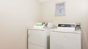 A laundry room with two white washing machines, a small cabinet, and a framed picture on the wall. - Super 8 by Wyndham Sullivan (Sullivan)