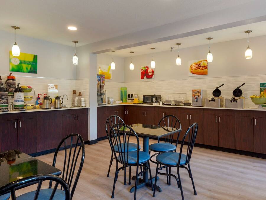 A modern kitchen with dark wooden cabinets, a central island with seating, and various kitchen appliances.