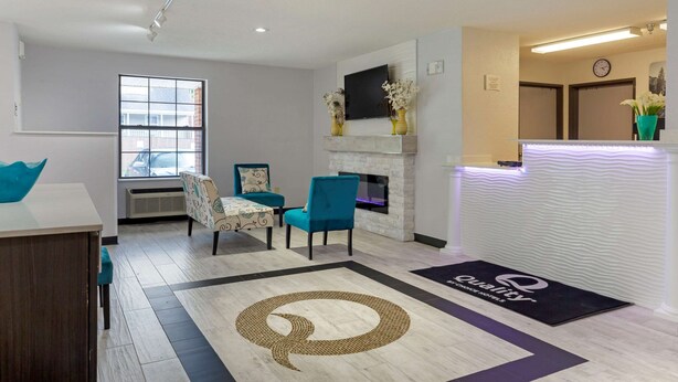 A reception area with a fireplace, seating, and a doormat with the logo "Quality". - Quality Inn Lee - Lenox South (Lee)