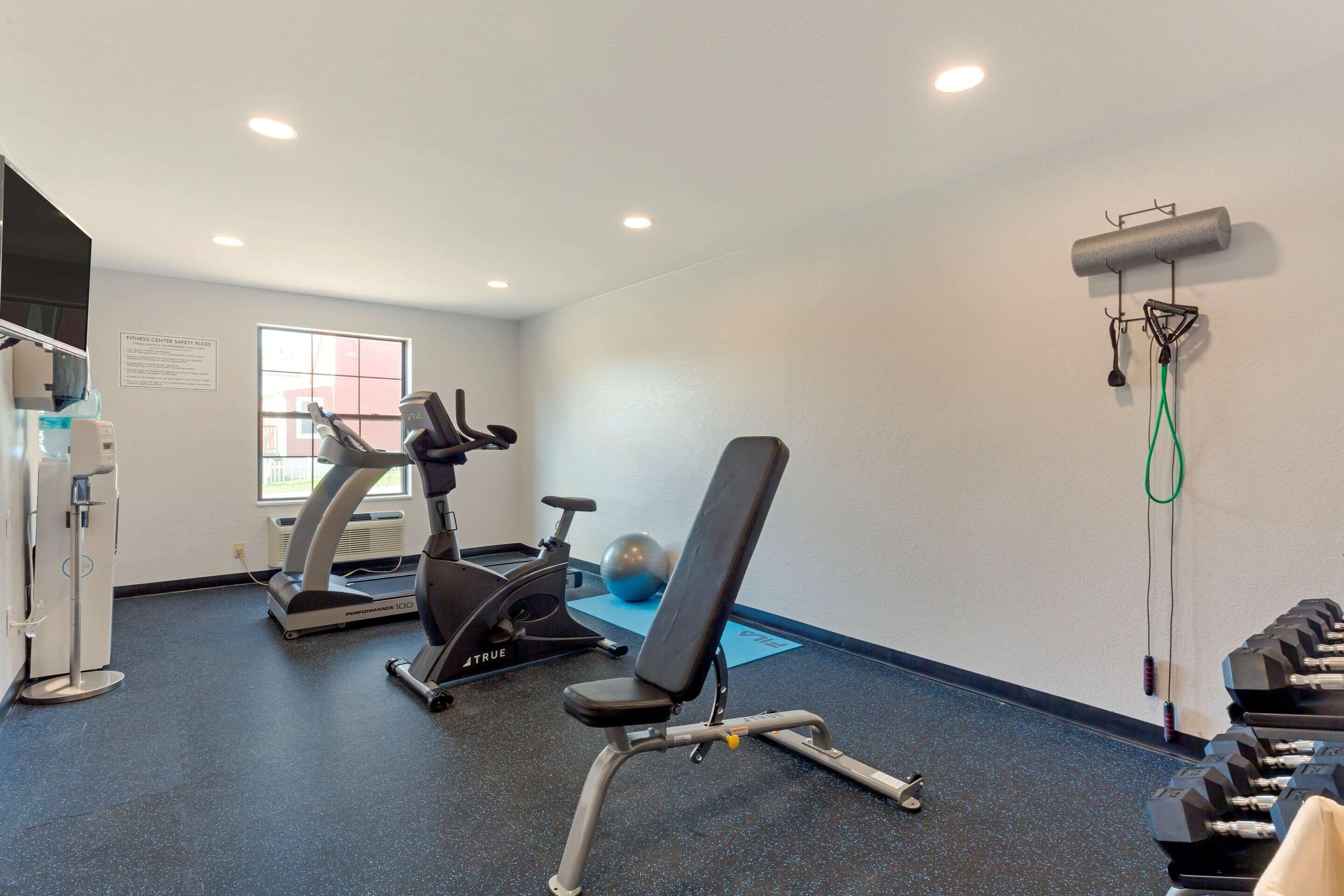 A gym with exercise equipment including treadmills, a stationary bike, and a bench.