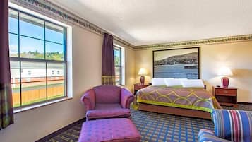 Ein Hotelzimmer mit großem Fenster, einem Bett, einem Sessel, einem Sofa und einem Gemälde an der Wand.