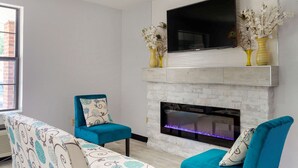 A modern living room with a fireplace, two blue armchairs, and decorative vases on the mantel. - Quality Inn Lee - Lenox South (Lee)