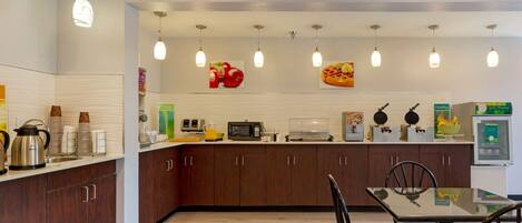 Una cocina moderna con armarios de madera, una mesa de comedor con sillas y electrodomésticos varios, como una cafetera y un microondas.