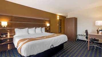 Una habitació d'hotel amb un llit gran, una taula de treball, una cadira, un armari i dues làmpades de nit.