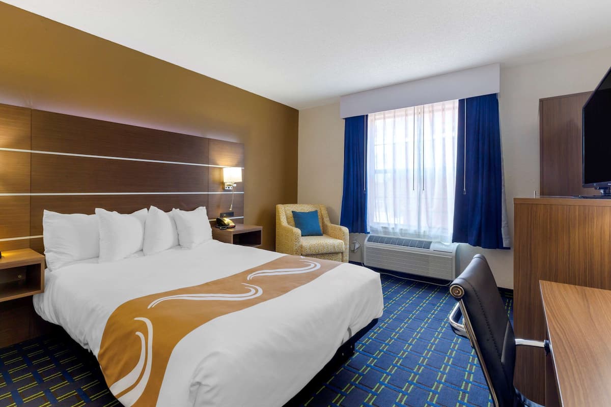 Una habitación de hotel con una cama grande, una silla, un escritorio y una televisión.