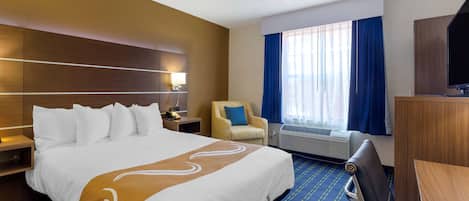 Una habitación de hotel con una cama grande, una silla, un escritorio y una televisión.