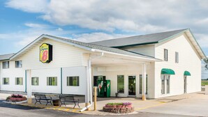 Un motel Super 8 con entrada cubierta, asientos exteriores y una máquina expendedora.