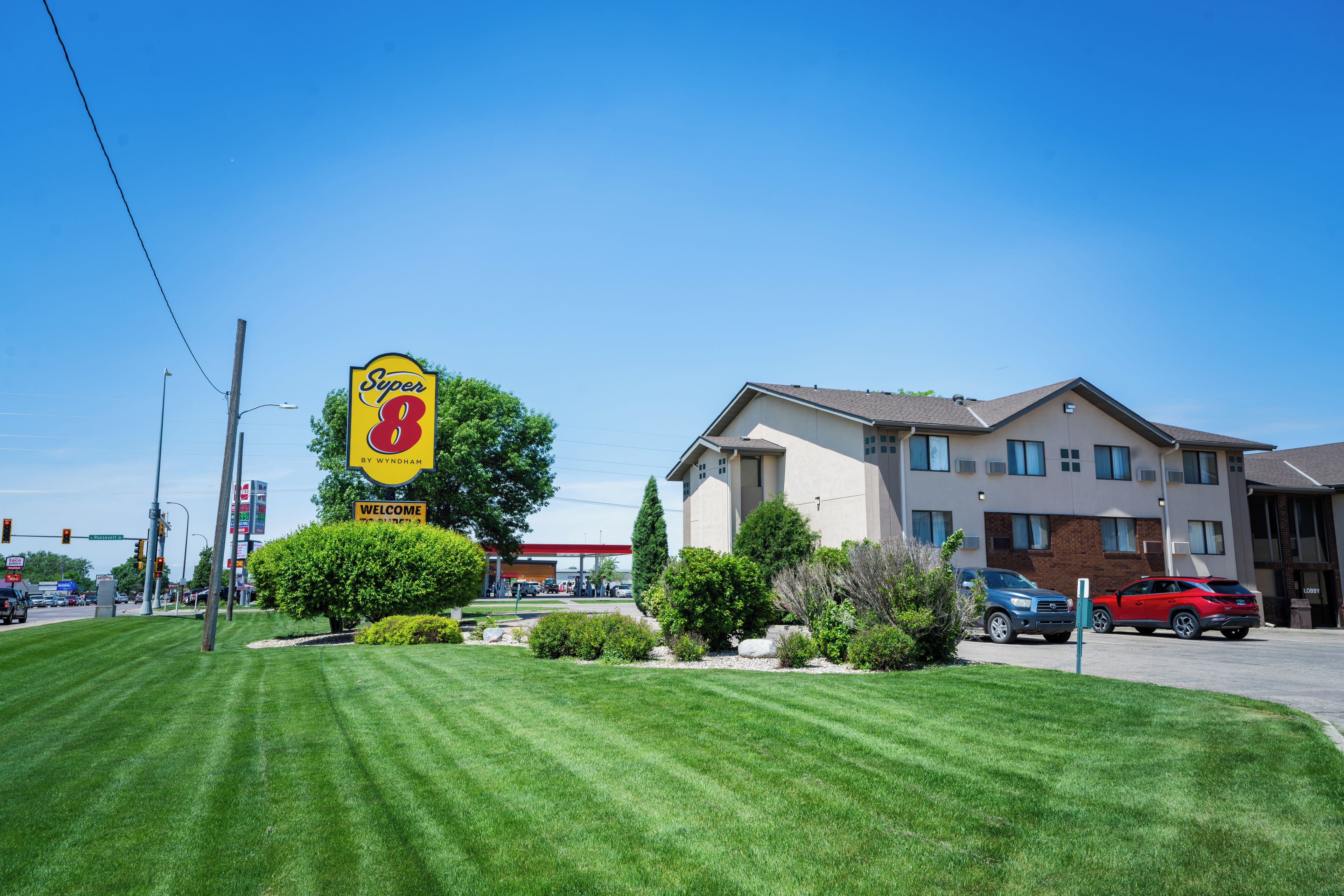 A Super 8 motel with a well-maintained lawn, a gas station, and a multi-story building with a modern design.