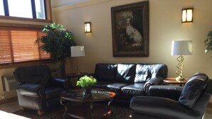 A living room with a black leather sofa, a glass coffee table, and a large potted plant. - Super 8 by Wyndham Aberdeen East (Aberdeen)