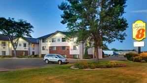 A Super 8 motel with a parking lot, a tree in the foreground, and a truck in the background. - Super 8 by Wyndham Aberdeen East (Aberdeen)