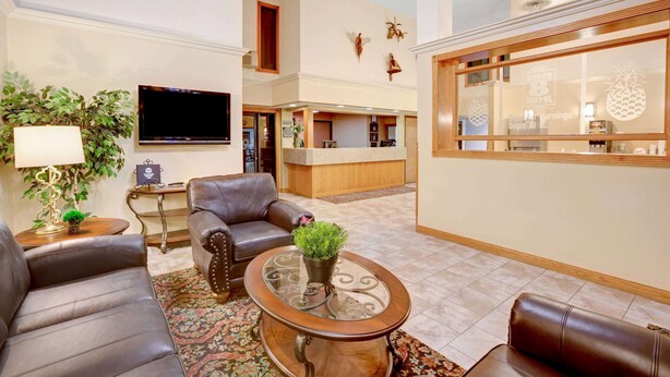 A hotel lobby with leather sofas, a glass coffee table with a plant, a flat-screen TV, and a reception desk. - Super 8 by Wyndham Aberdeen East (Aberdeen)