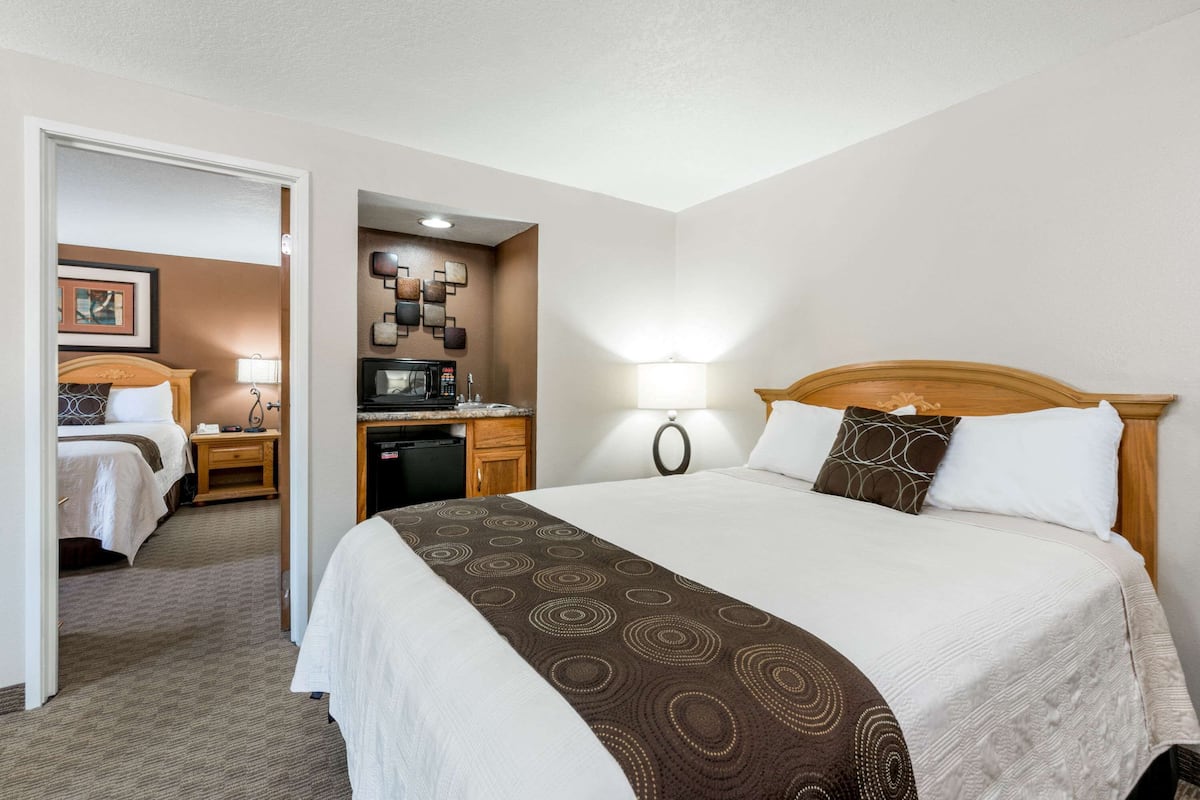 Una habitación de hotel con una cama grande, un escritorio, un microondas y una pequeña cocina.