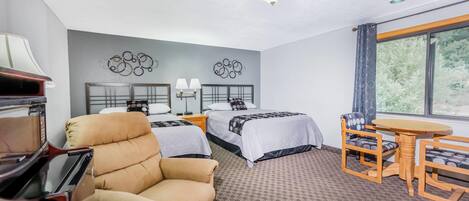 A hotel room with two beds, a sofa, a desk, and a dining table.