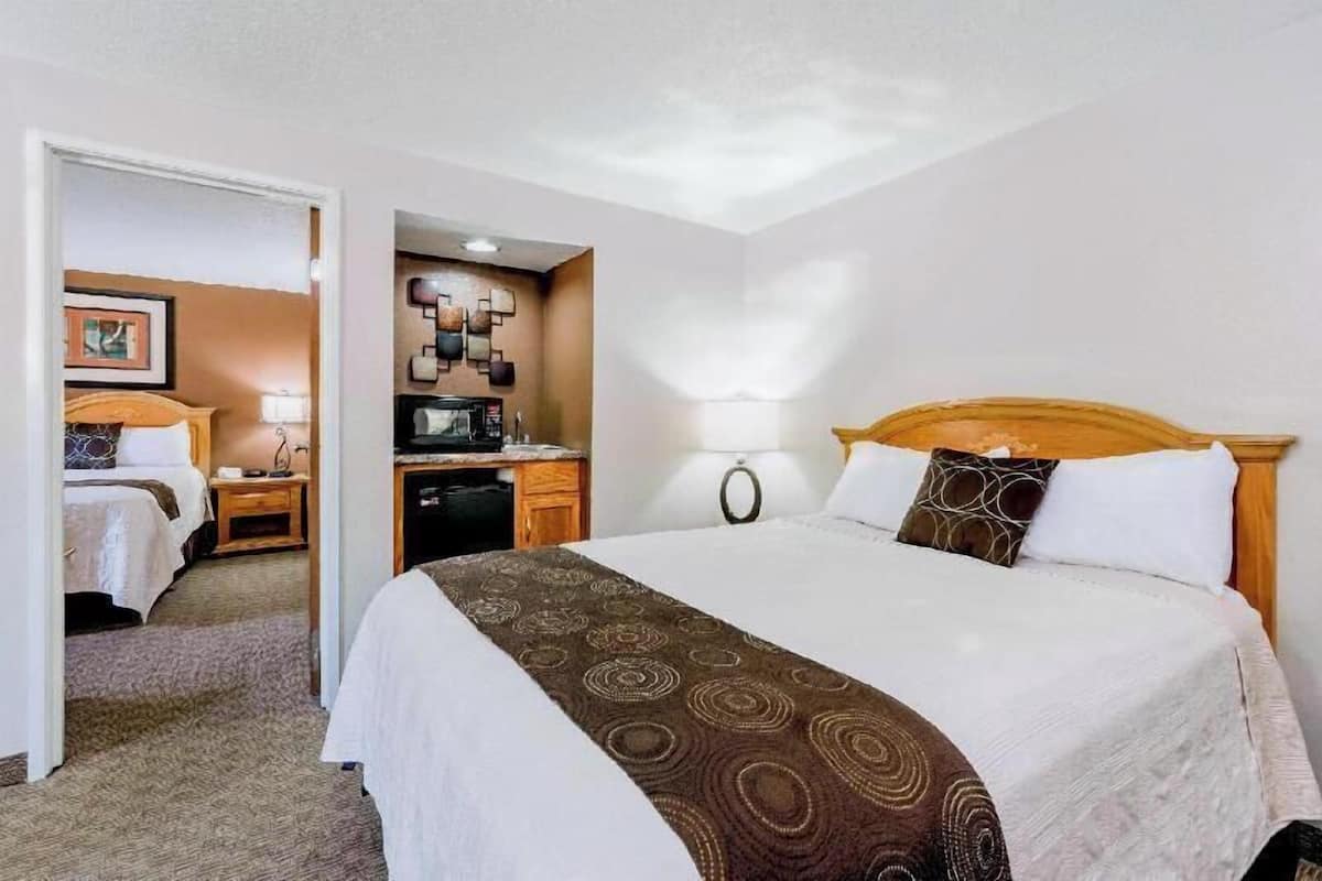 Habitación de hotel con cama, escritorio, silla, lámpara y televisor montado en la pared.
