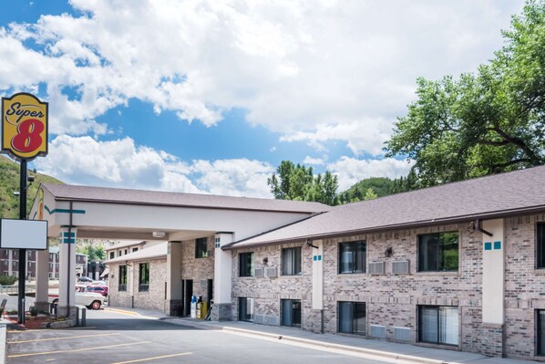 A Super 8 motel with a brick facade, multiple rooms, and a gas station. - Super 8 by Wyndham Deadwood / Black Hills Area (Deadwood)