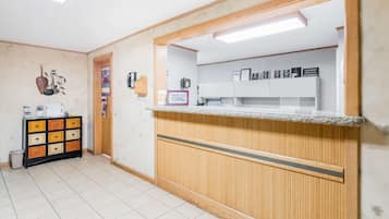 Ein Empfangsbereich mit einem Holzbüro, einem Fliesenboden, einer kleinen Kommode und einem an der Wand befestigten Regal mit gerahmten Zertifikaten.