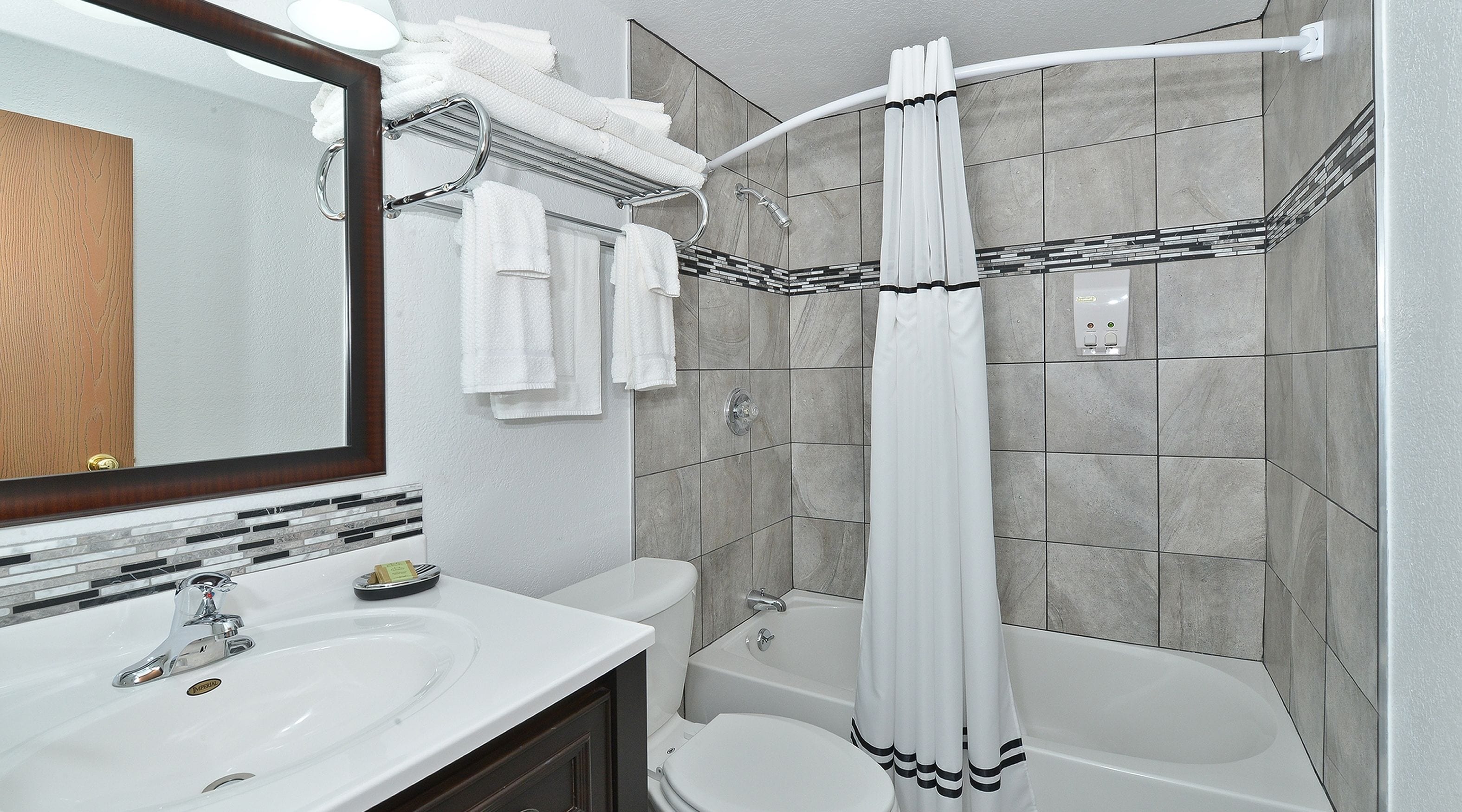 A bathroom with a vanity, sink, mirror, and a shower with a curtain.