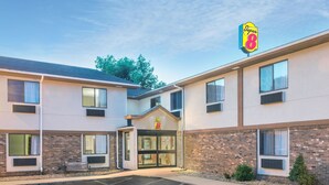 A Super 8 hotel with a brick facade, large windows, and a parking lot. - Super 8 by Wyndham Tilton/Lake Winnipesaukee (Tilton)