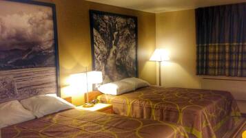 A hotel room with two beds, a nightstand, a lamp, and a large painting on the wall.