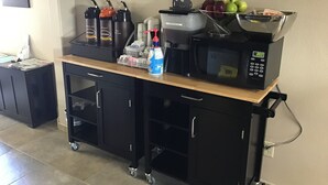 Una kitchenette con microondas, cafetera y varios utensilios de cocina en un carrito.