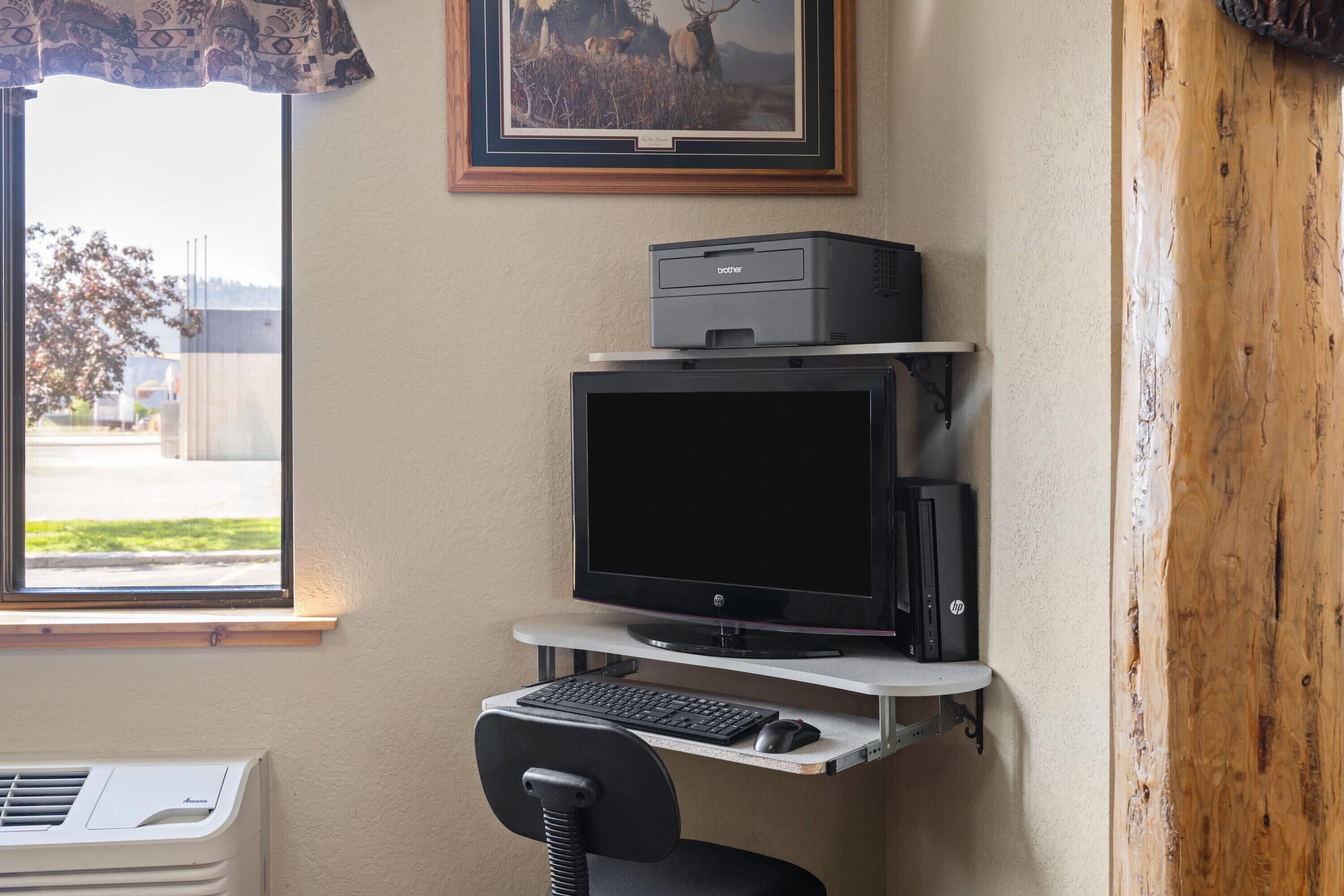 A home office setup with a desktop computer, printer, and chair.