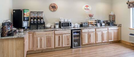 A kitchen with wooden cabinets, a refrigerator, a coffee machine, a microwave, and a toaster.