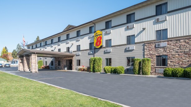 A Super 8 motel with a stone facade, a covered entrance, and a parking lot. - Super 8 by Wyndham Kalispell Glacier National Park (Kalispell)