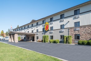 Un motel Super 8 con fachada de piedra, un acceso cubierto y un estacionamiento.
