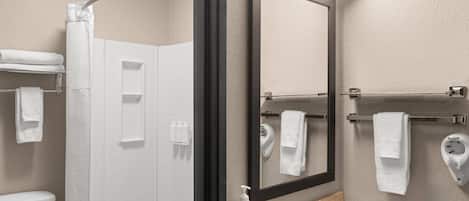 A modern bathroom with a shower, toilet, sink, and a large mirror.