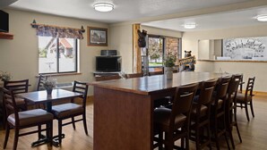 A spacious kitchen with a large island, wooden chairs, and a dining table. - Super 8 by Wyndham Kalispell Glacier National Park (Kalispell)