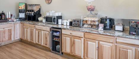A breakfast area with a coffee machine, microwave, toaster, and a refrigerator with shelves.