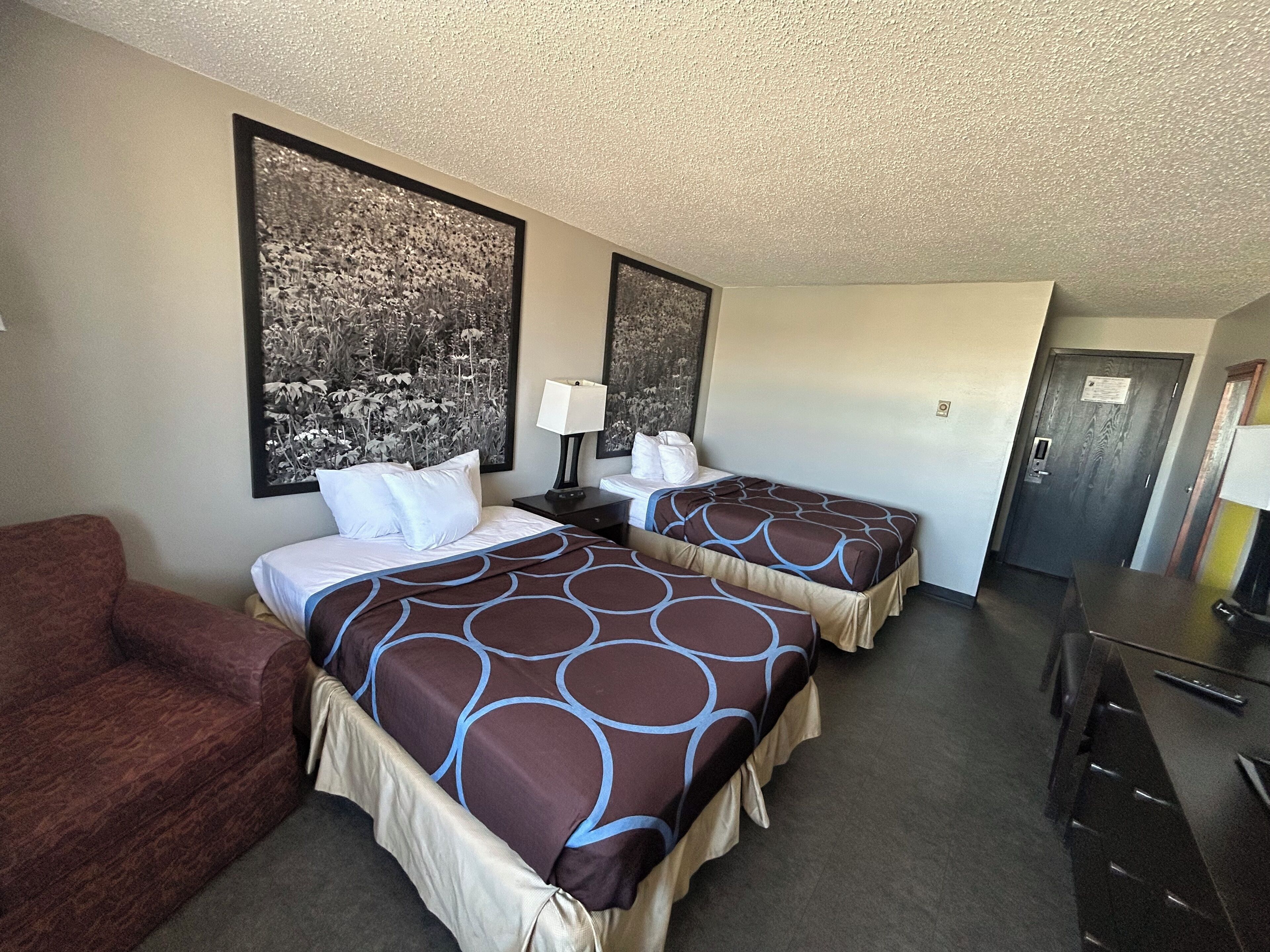 A hotel room with two beds, a desk, and a couch.