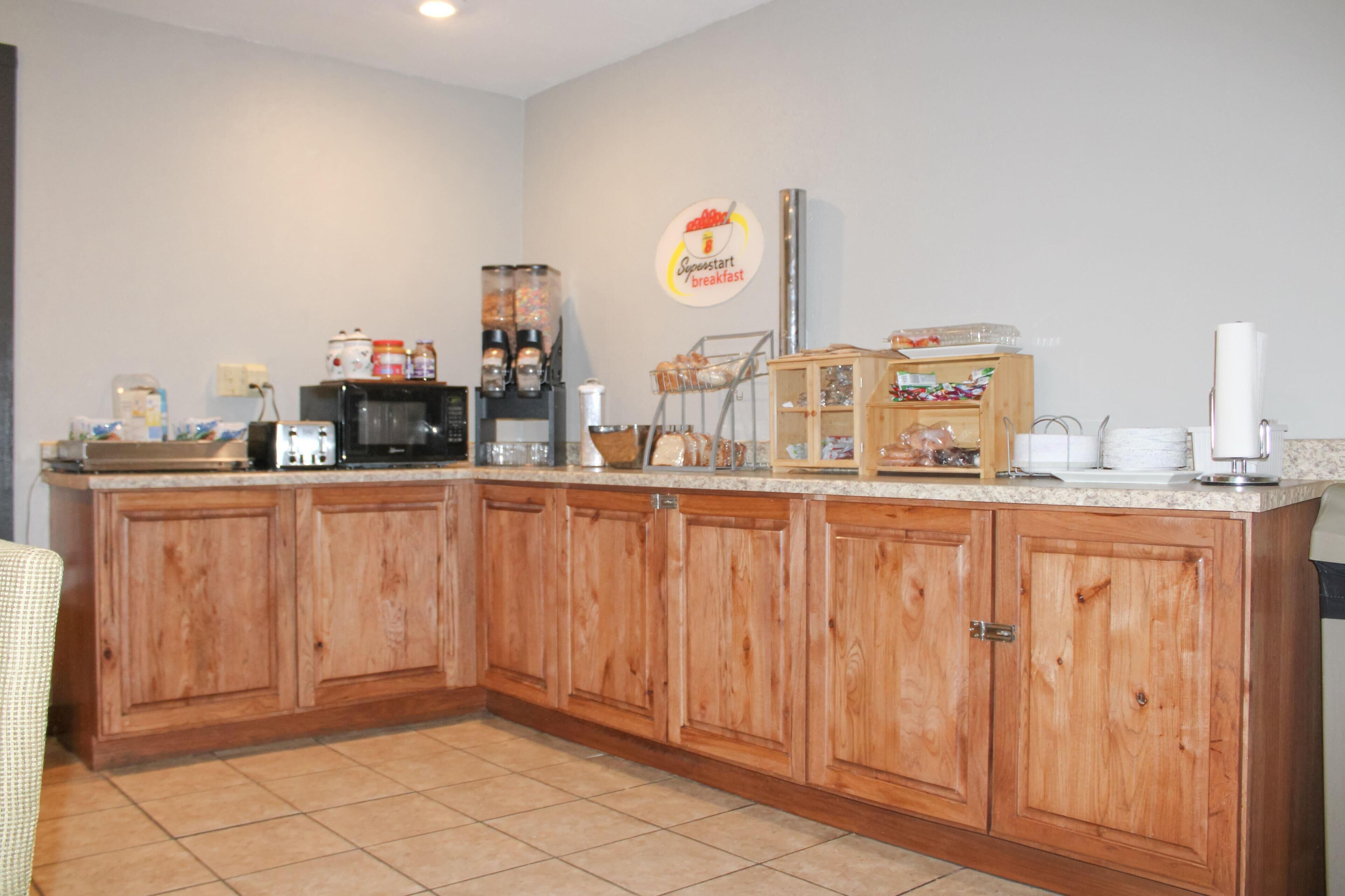 Una cocina con armarios de madera, una estación de café y un letrero de desayuno en la pared.