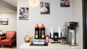 Una estación de café con una máquina de café, dos dispensadores de café, una taza de café y un molinillo.