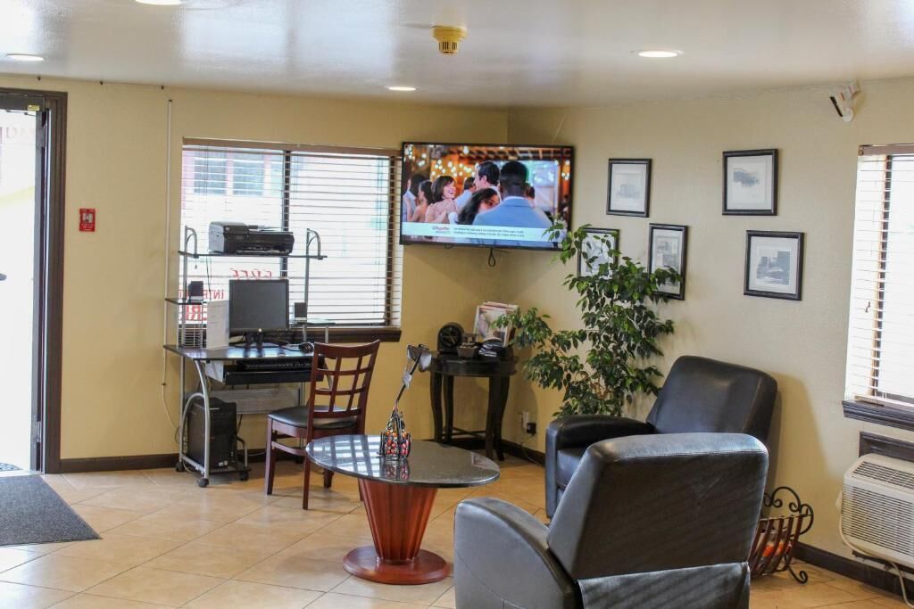 A waiting area with a television, chairs, a coffee station, and framed pictures on the wall.