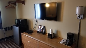 A hotel room with a flat-screen TV mounted on the wall, a mini-fridge, a microwave, a coffee maker, and a small cabinet with a picture frame. - Super 8 by Wyndham Carson City/Lake Tahoe (Carson City)