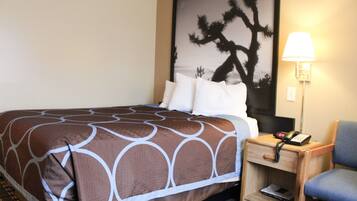 A hotel room with a bed, a nightstand with a lamp, and a chair.