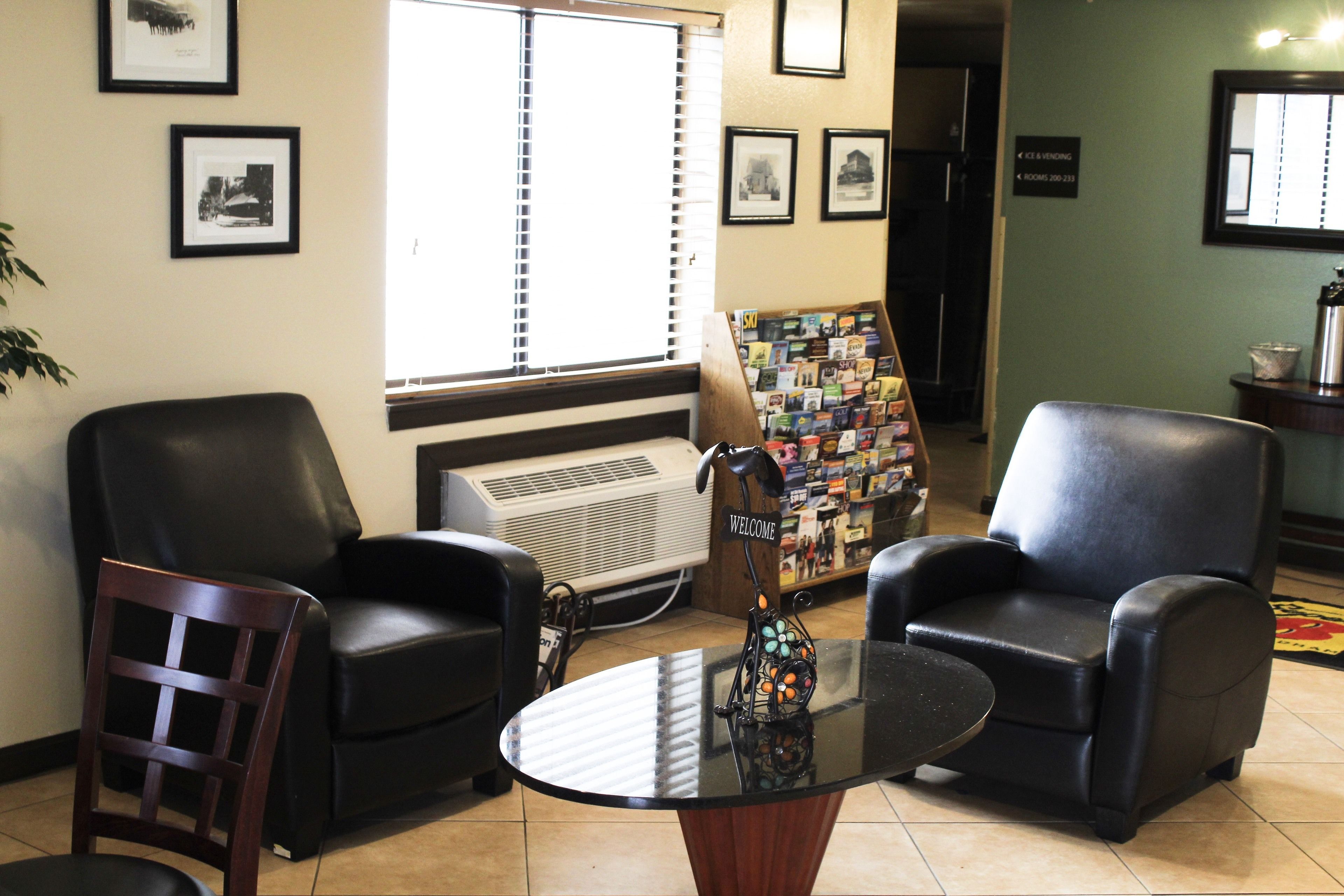 A reception area with two black leather chairs, a glass table, and a welcome sign.