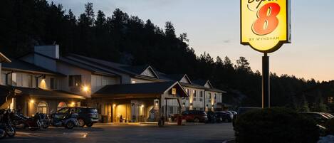 Un hotel con un llamativo letrero de 'Super 8', varios espacios de estacionamiento y un edificio de techo inclinado.