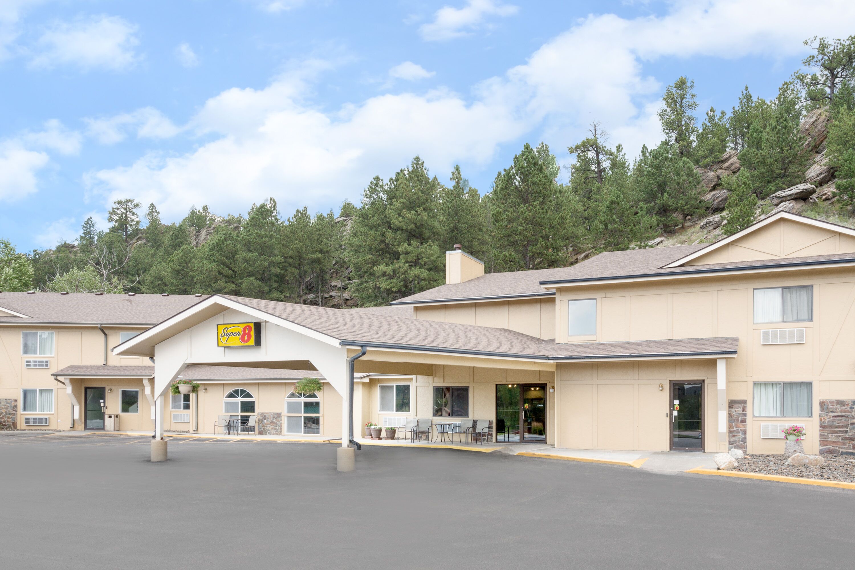 Un motel con entrada techada, asientos al aire libre y un letrero que indica que es un Super 8.