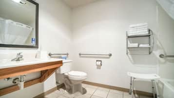 A bathroom with a white sink, toilet, and a small white stool. There is a mirror above the sink and a towel rack on the wall.