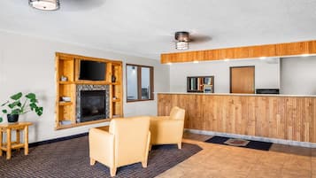 A reception area with a wooden reception desk, two leather chairs, a fireplace, and a potted plant.