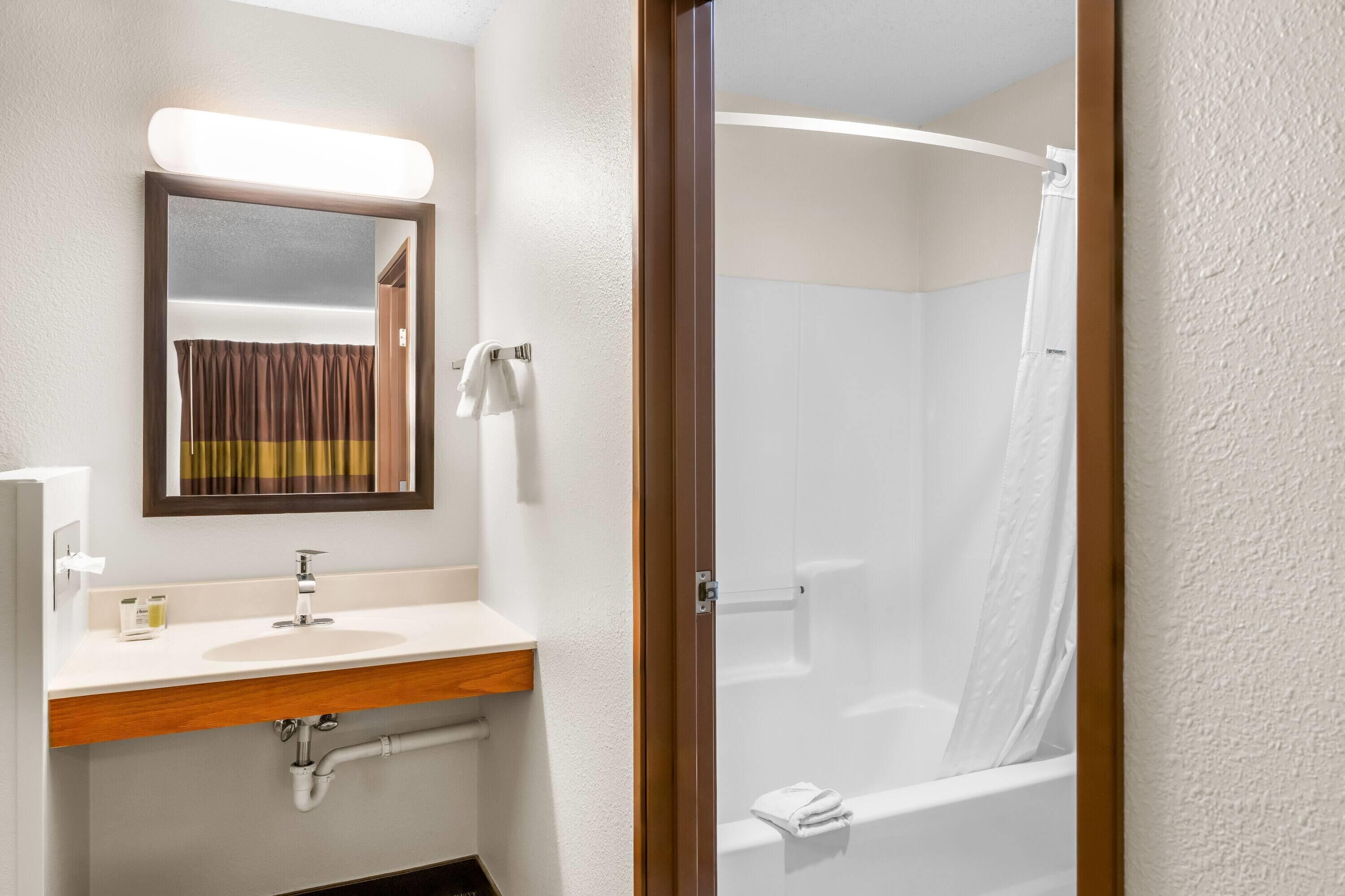Un baño con lavamanos, espejo y ducha.