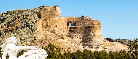 A large rock formation with a statue of a man and horse, and a construction crane in the background.