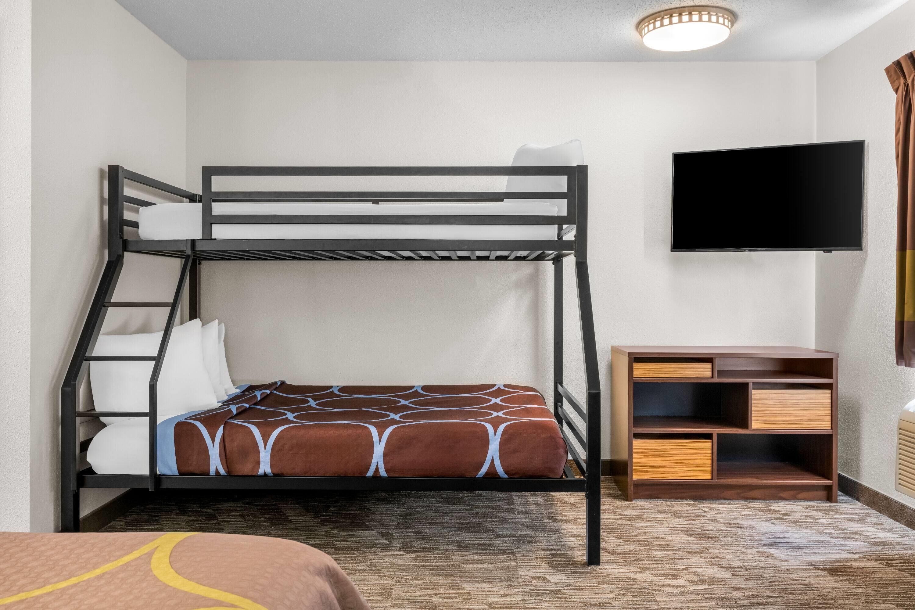 A bunk bed with a TV above it, a wooden cabinet, and a patterned carpet.