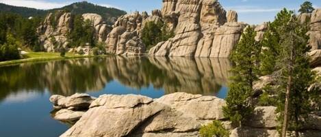 A serene lake with large boulders and trees in the foreground.