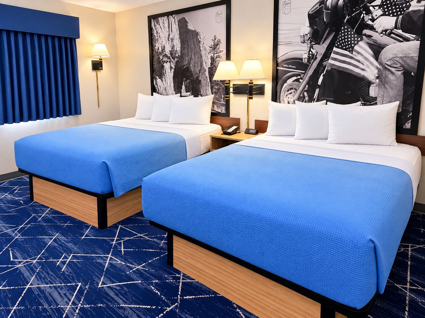 Ein Hotelzimmer mit zwei Betten, einem blauen Teppich und einer Wandlampe.