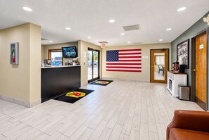 Un vestíbulo de hotel con mostrador de recepción, una bandera estadounidense y una estación de café.