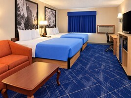 Habitación de hotel con dos camas, un escritorio, una silla, un televisor y un sofá.
